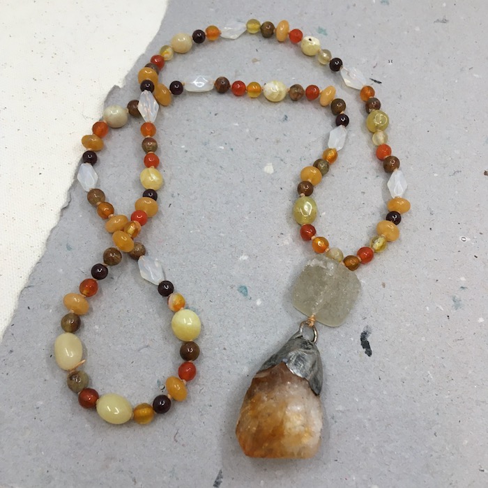 Rough yellow orange stone pendant with solder top, light yellow druzy stone with variety of shapes and sizes of beads in yellows, dark garnet, brown and yellow made into a necklace.