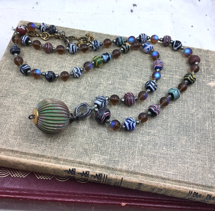 Necklace with patina brass bead, and a variety of glass beads with stone spacers. 