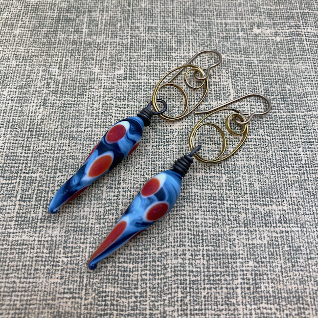 Earrings with red, white and blue glass headpins on triple circle brass connectors. 