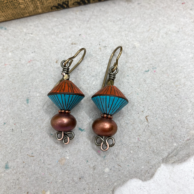 Earrings with rust and turquoise bicones with black lines, bronze beads and clover metal headpins.