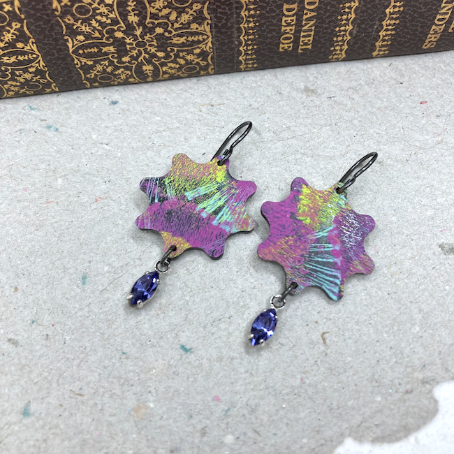 Earrings in star flower shape with graffiti-like colors in purple, yellow, blue, white and heliotrope crystal drops. 